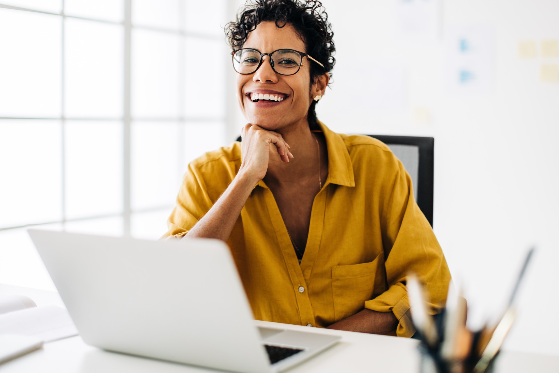 Femme d’affaires professionnelle souriant à la caméra. Femme assise à son bureau